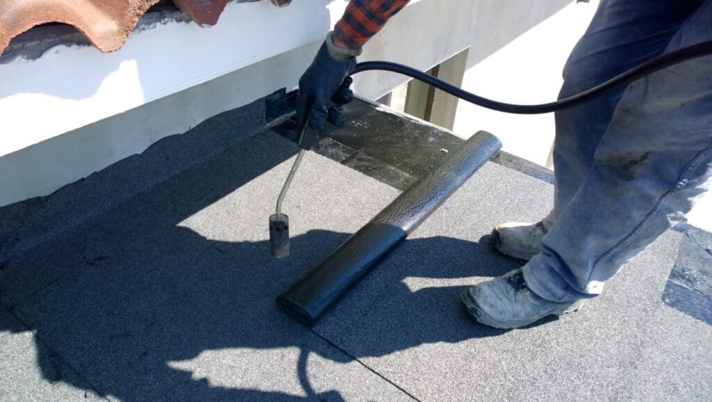 Workers preparing a flat roof covering with a torch