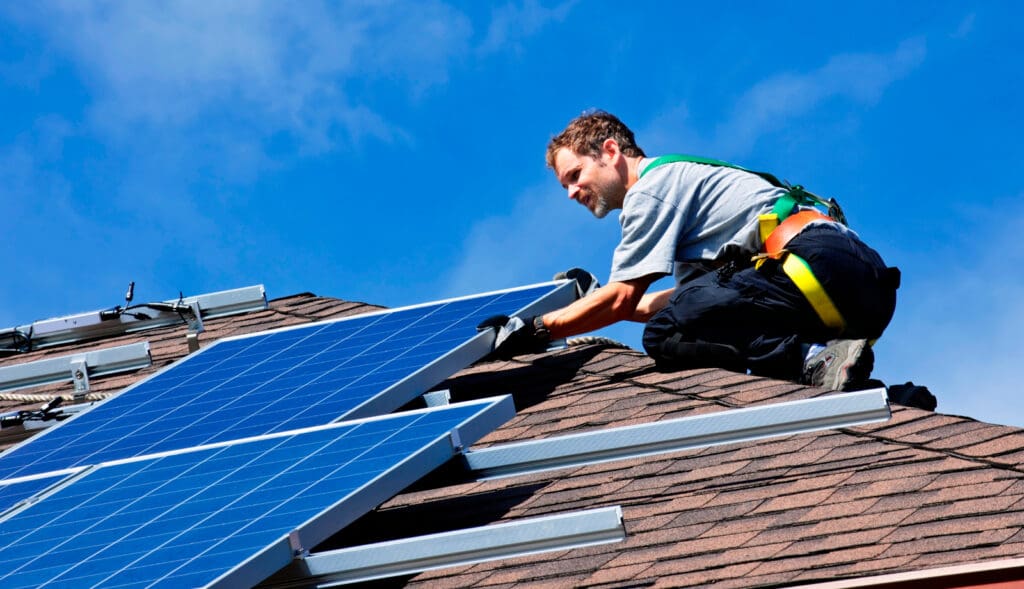 Man installing alternative energy photovoltaic solar panels on roof
