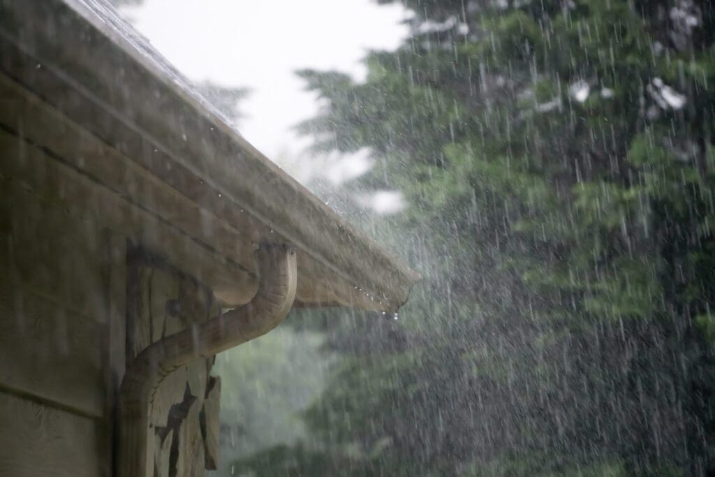 heavy rain pouring down from passing storm with gutter system on a home managing the water to illustrate Importance of Gutter Installation in the Pacific Northwest
