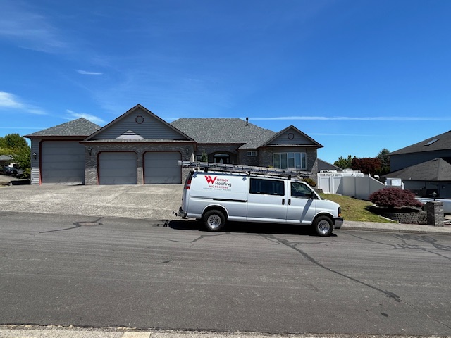 A Warner Roofing and Construction van in front of a home with a new roof.