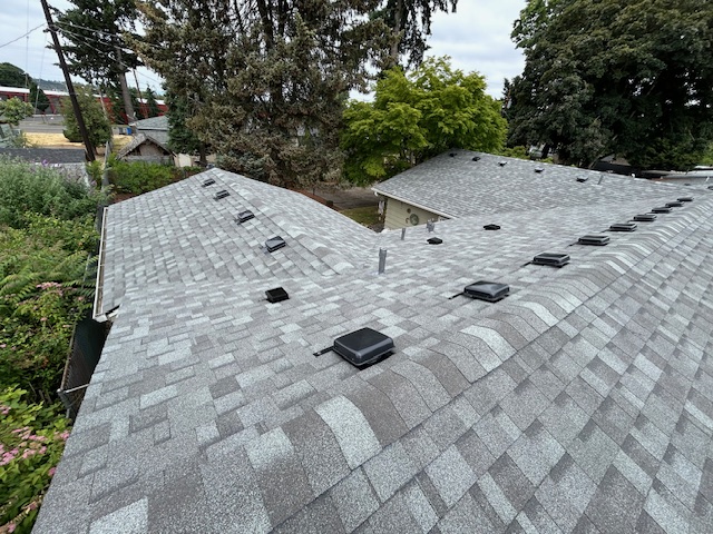 A home with a gray asphalt shingles roof with vents and a skylight.