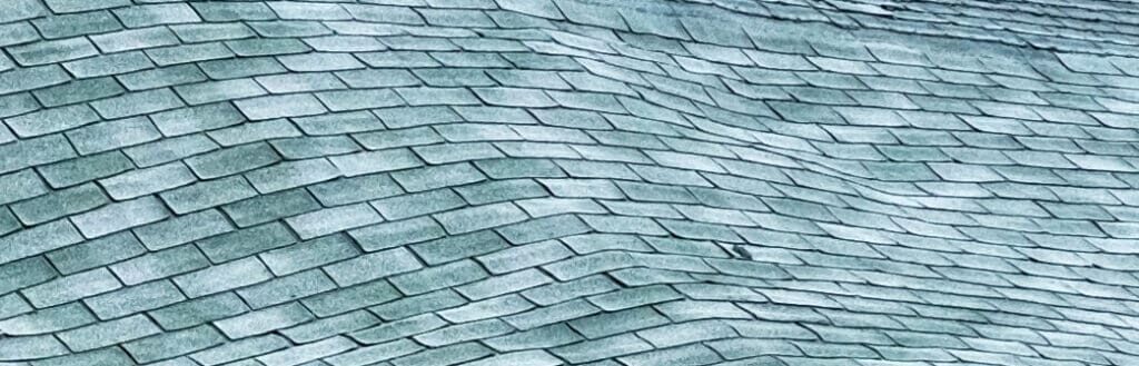 An asphalt shingle roof that is wavy to help illustrate roof inspection services