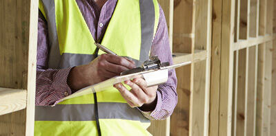 A man in a yellow vest writing on a clipboard