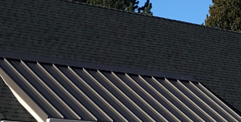 A metal overhand coming of a roof with shingles to help illustrate school roofing installation