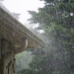 heavy rain pouring down from passing storm with gutter system on a home managing the water to illustrate Importance of Gutter Installation in the Pacific Northwest