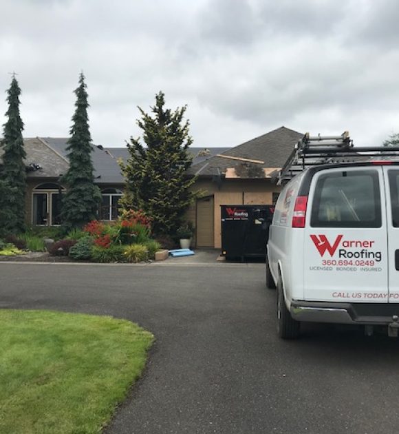 A Warner Roofing van in front of Vancouver, WA home getting a new roof installed