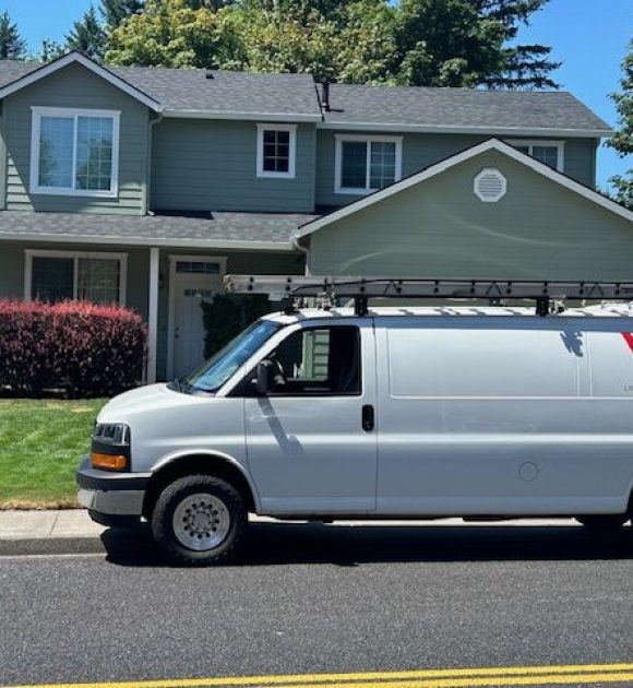 Warner Roofing and Construction work van in front of a house with a new roof to help illustrate roof replacements