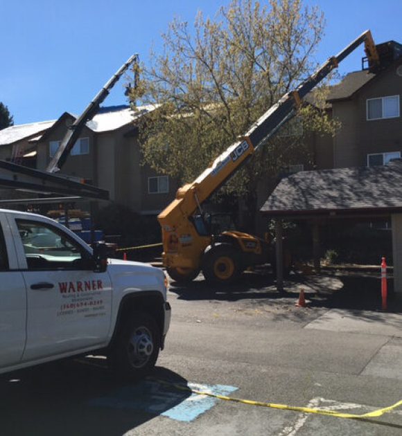 The Warner Roofing truck and roofing loading machines prepping roofs in an apartment complex to help illustrate roof replacements