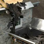 A person removing shingles from a house - How Long Does a Roof Tear Off Take?